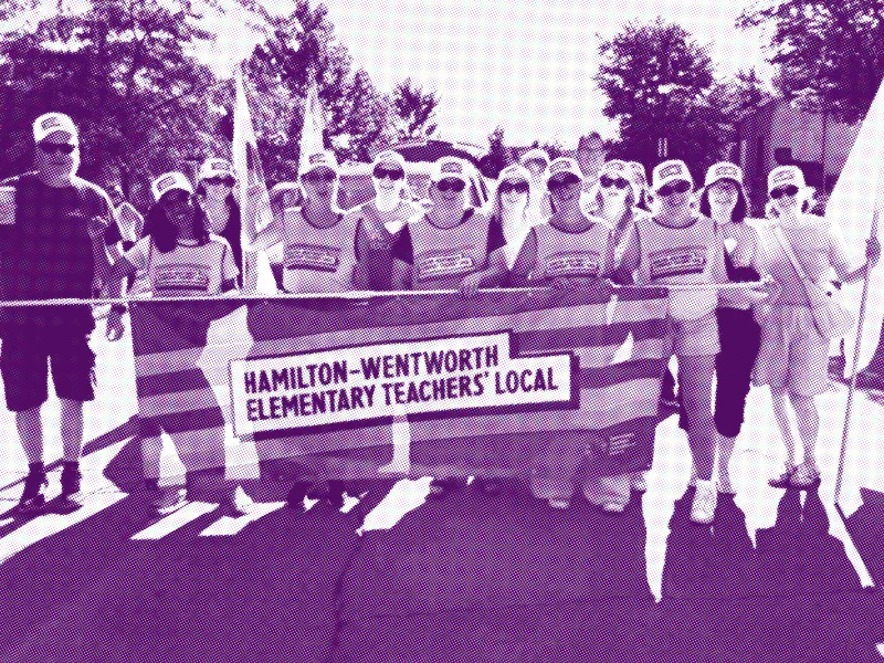 Purple-tinted photo with halftone effect showing current HWETL members out demonstrating, carrying a large banner with the HWETL logo.